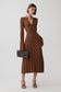 A woman models a brown ribbed long-sleeve midi dress with a button front and V-neckline, holding a black quilted handbag against a light gray studio background.