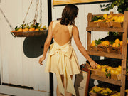 Image of woman in lemon sherbet backless mini dress.