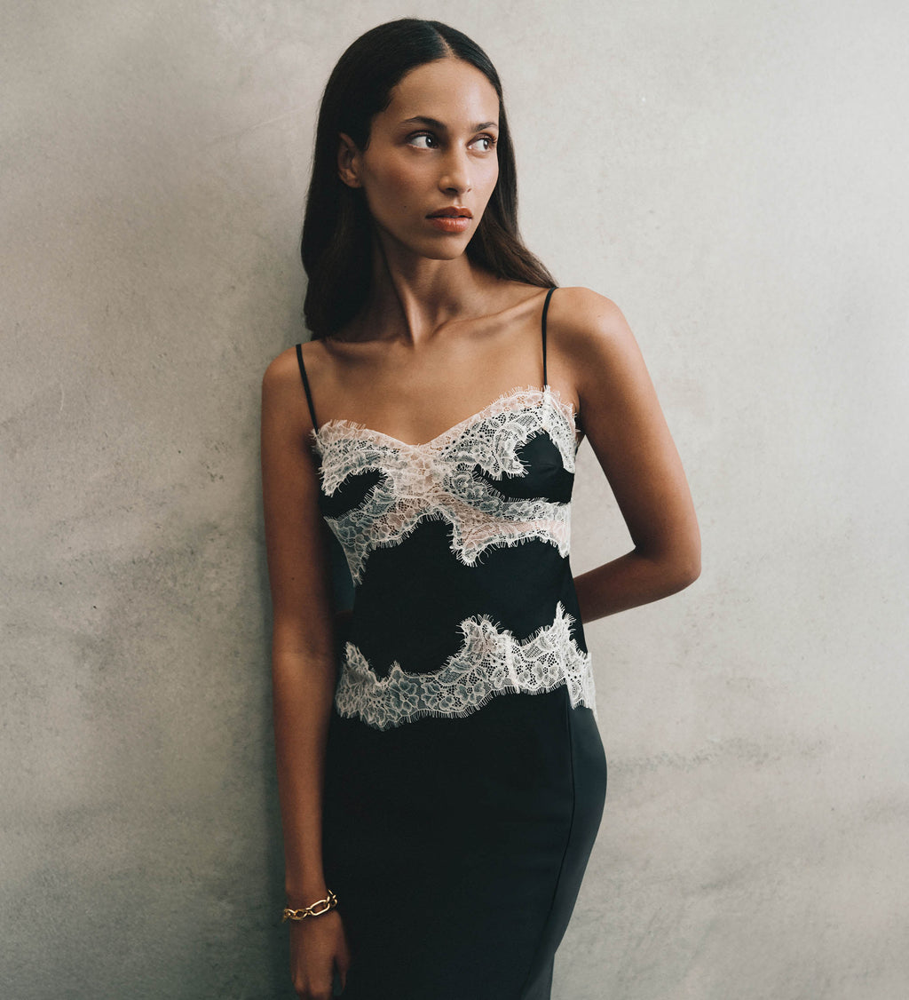 Woman wearing a black and white lace top against a plain background.