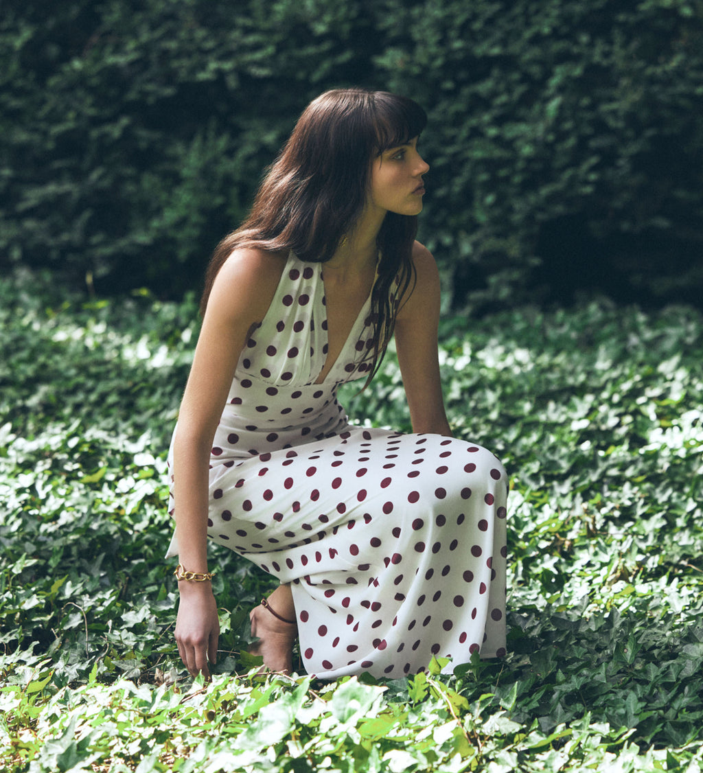 Woman in a polka dot dress sitting on the grass.