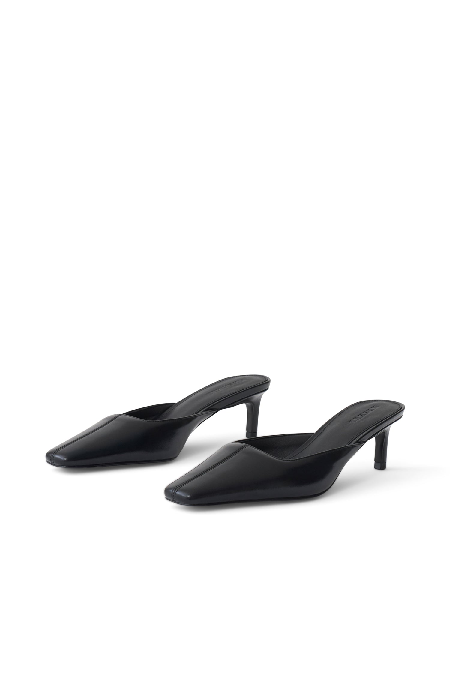 A pair of black pointed-toe mule heels with slim kitten heels, shown from a three-quarters angle on a clean white background.