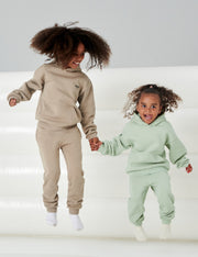 Image of two children jumping in jumping castle wearing matching beige and mint green tracksuits