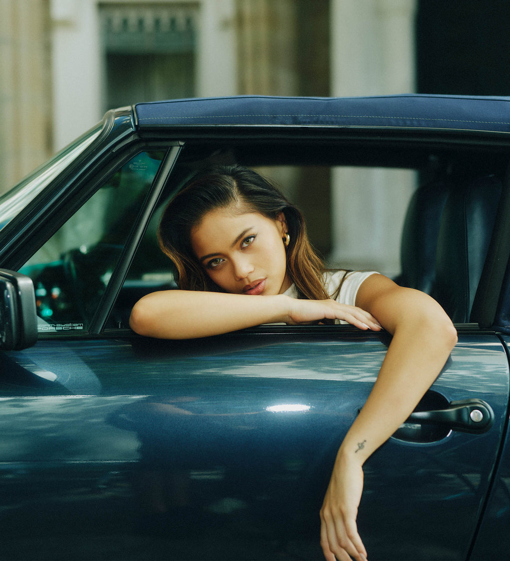 Woman leaning out of a car window in an urban setting.