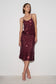 A woman modeling a sleeveless, spaghetti-strap top with matching midi skirt covered in dark burgundy sequins, standing against a plain white studio background.