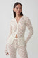 A woman modeling a matching cream-colored crochet knit cardigan and pants set against a plain light gray studio background.