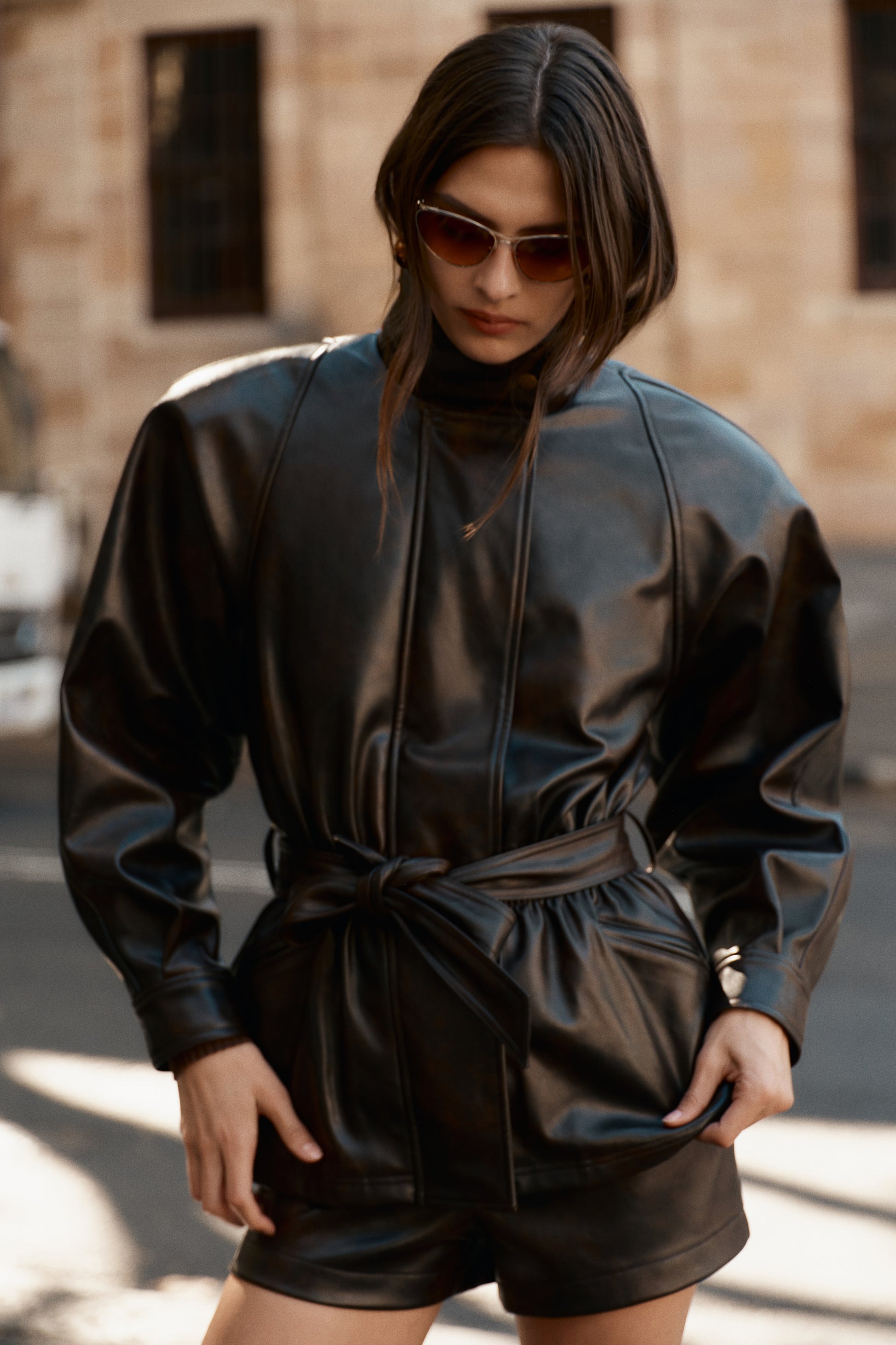 Woman wearing a dark brown faux leather cinch waist jacket.